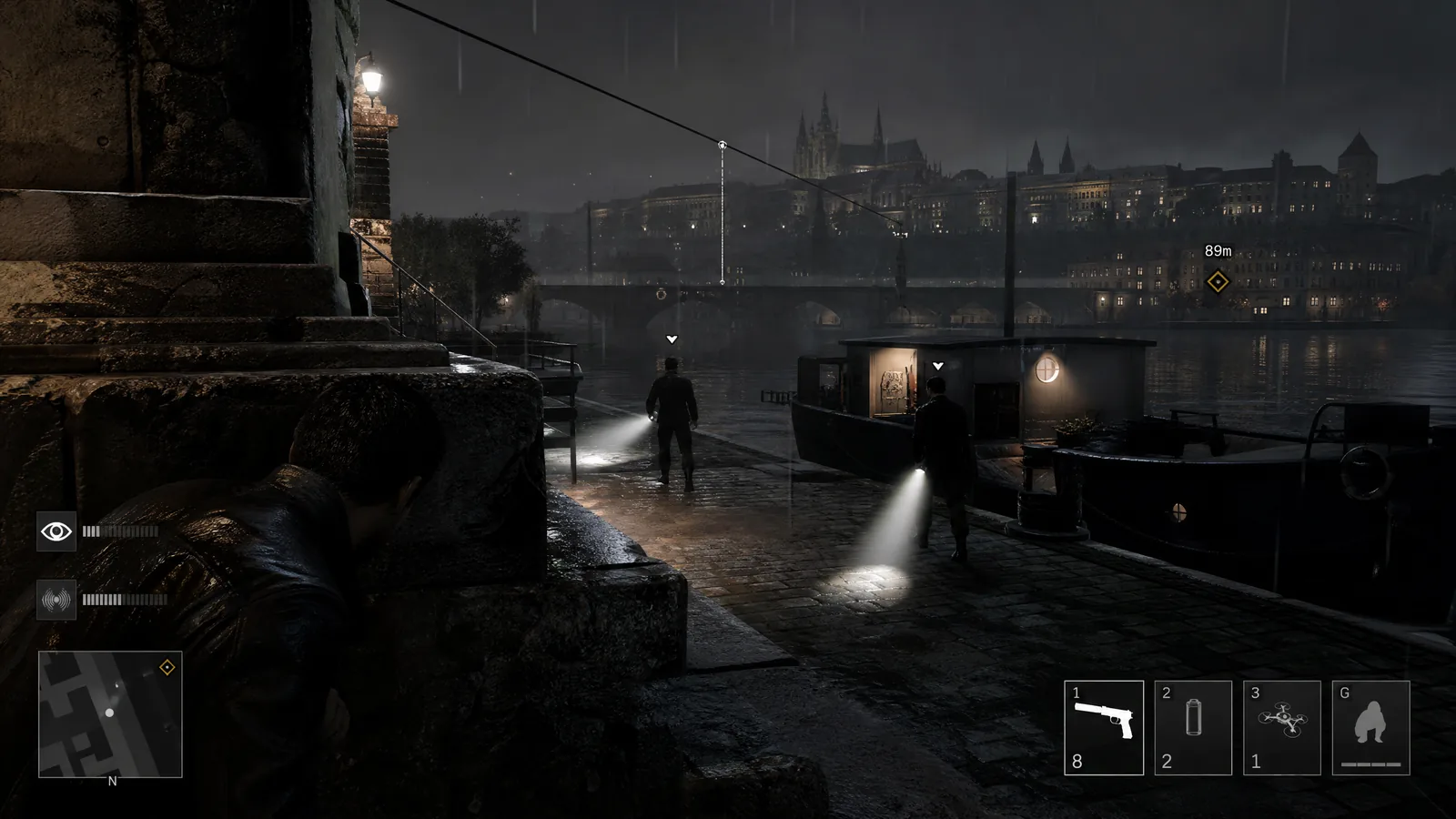 Stealth gameplay na deštivém nábřeží s ukrytou postavou, hlídkami, kužely světla, řekou a HUD viditelnosti.